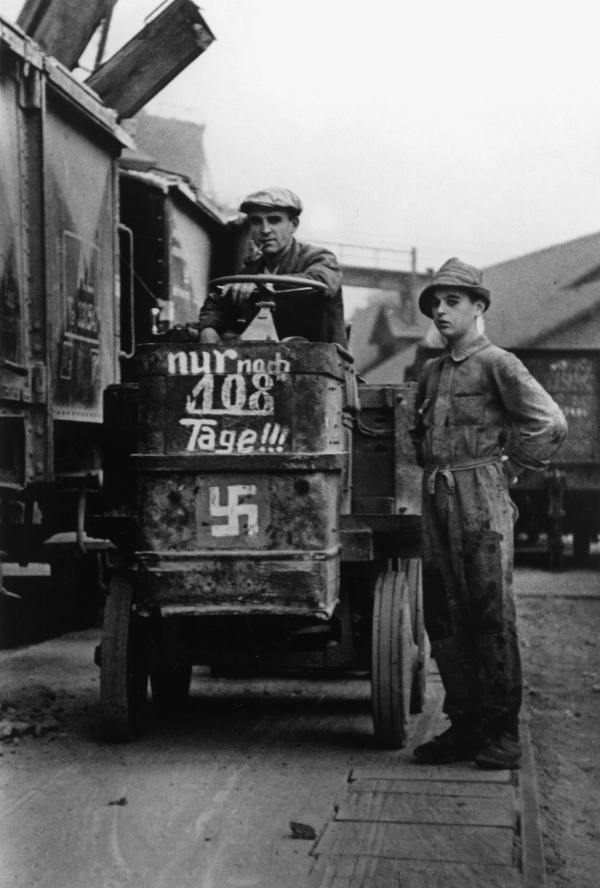 2 Männer stehen vor einem Wagen. Auf diesem steht "nur noch 108 Tage" und ein Hakenkreuz